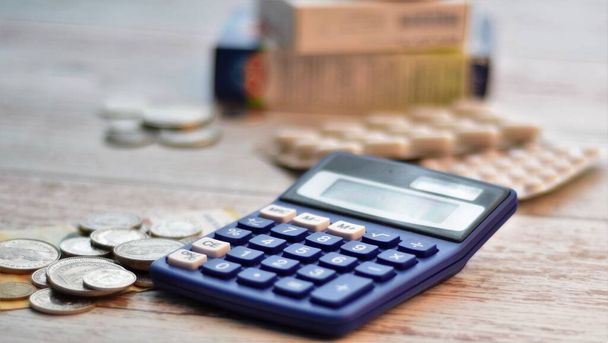 rekenmachine, geld en tabletten op een houten tafel - Foto, afbeelding