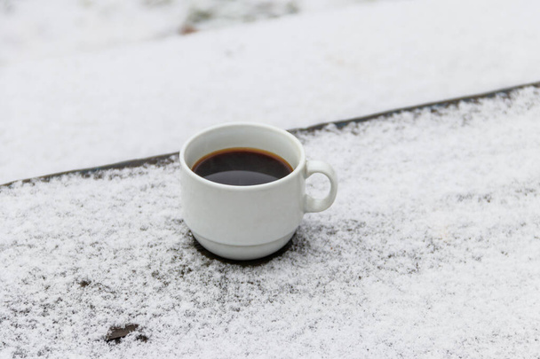 Xícara de café em uma mesa coberta de neve no inverno - Foto, Imagem