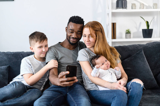 A multiracial family on the couch at home - Φωτογραφία, εικόνα
