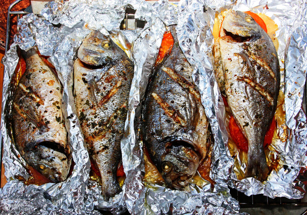 vier gebakken dorado vis met groenten, bovenaanzicht, feestelijk familiediner - Foto, afbeelding