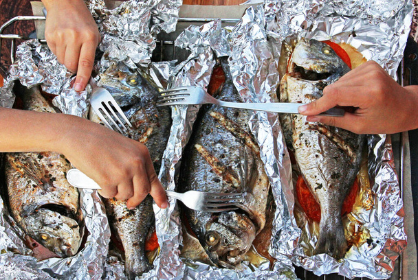 pesce dorado al forno in lamina con verdure per una cena di vacanza in famiglia, mani di bambini con una forchetta che raggiunge per il pesce - Foto, immagini