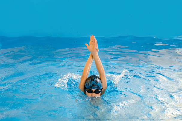Menino nadando na piscina interior se divertindo durante a aula de natação - Foto, Imagem