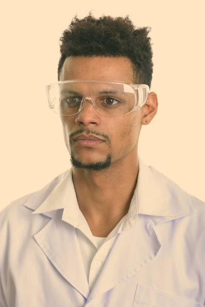 Young African man doctor thinking while wearing protective glasses - Foto, immagini