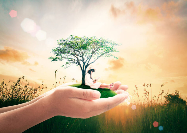 Concepto del programa mundial de autismo para la salud pública: las manos del maestro sosteniendo un hermoso árbol y una niña leyendo sobre el fondo del atardecer de otoño - Foto, imagen