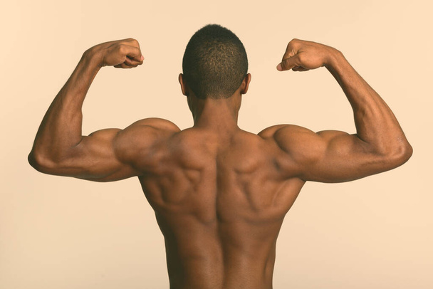 Młody muskularny Afrykanin bez koszulki napinający obie ręce - Zdjęcie, obraz