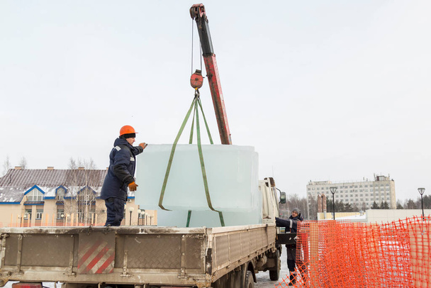 Assemblers unload ice panels from a car using a crane - Photo, Image