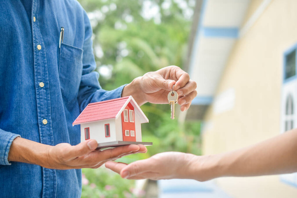 Sprzedawca daje dom klucz do wynajmu klienta kupić nieruchomości inwestycji biznesowych, Klucz gospodarstwa ręcznego i model domu - Zdjęcie, obraz