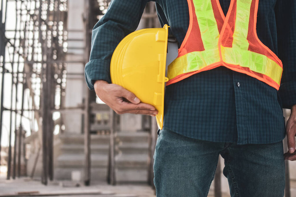 Close worker holding hard hat on site construction background - Zdjęcie, obraz