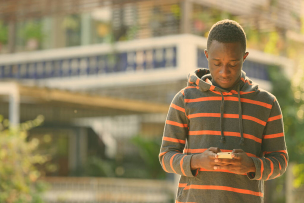 Fiatal afrikai férfi mobiltelefont használ a szabadban - Fotó, kép