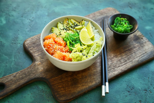 Cuenco con sabroso arroz, pescado y verduras sobre fondo de color - Foto, imagen