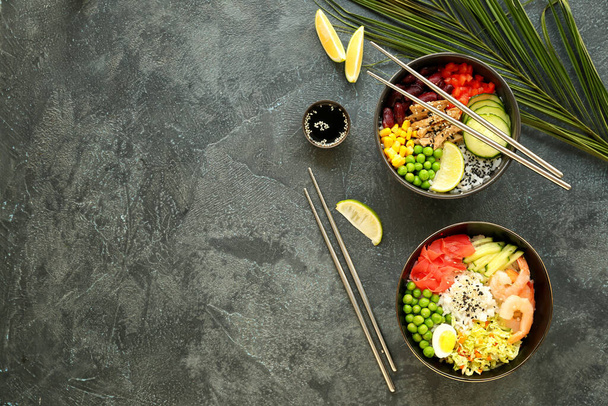 Bowls with tasty rice, shrimps and vegetables on dark background - Photo, Image