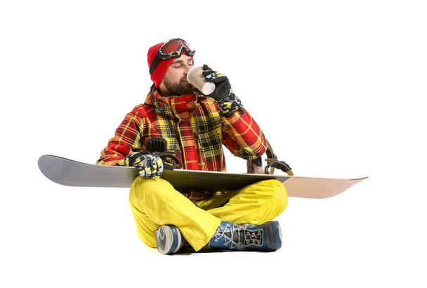 Male snowboarder drinking coffee on white background - Φωτογραφία, εικόνα