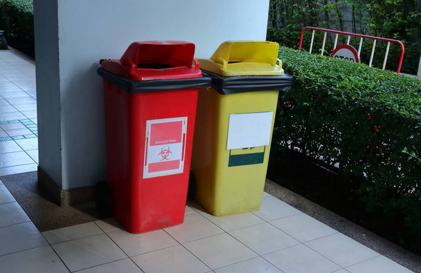 Detailní biohazard koš vedle žluté recyklační koše proti modré zdi  - Fotografie, Obrázek