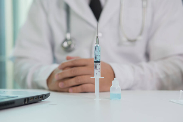 Maskierter Arzt nimmt Impfstoff mit Spritze  - Foto, Bild