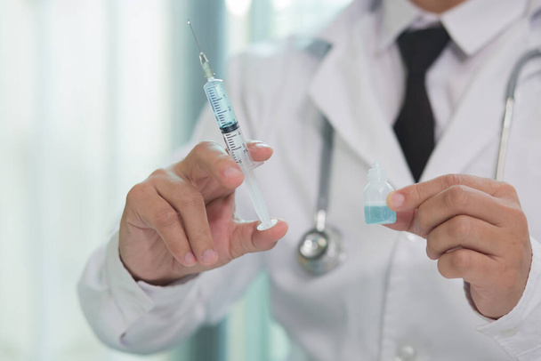 Lääkäri maskissa ottaen rokote ruiskulla  - Valokuva, kuva