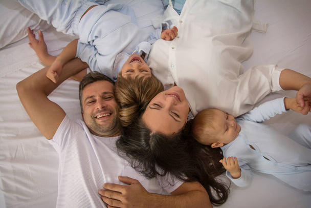 Portrait Of Happy Family Wearing Pajamas In Bed. Family Playing In Bed With Her Children. Family Lifestyle. - Фото, зображення