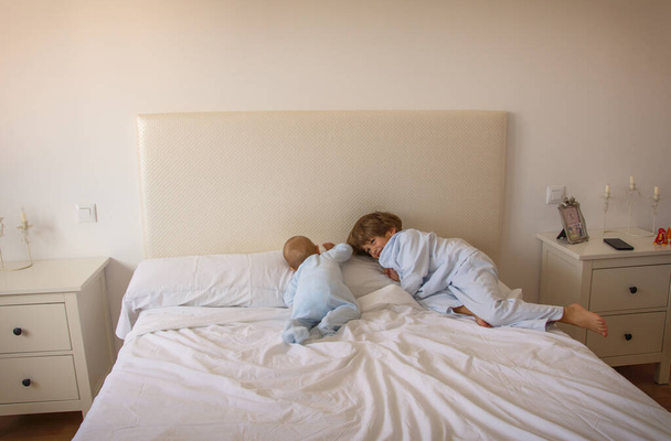 Fratelli che giocano sul letto in pigiama. Stile di vita familiare - Foto, immagini