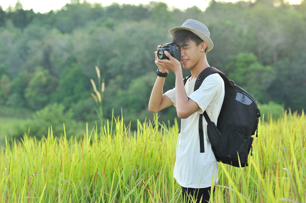Νεαρός Ασιάτης ταξιδιώτης με σακίδιο που τραβάει μια φωτογραφία και κοιτάζει την καταπληκτική λίμνη. Ταξιδιωτική έννοια χαλάρωσης διακοπών - Φωτογραφία, εικόνα