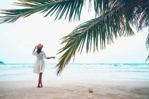 Rückansicht einer Touristin, die am Strand in Richtung Meer steht - Foto, Bild