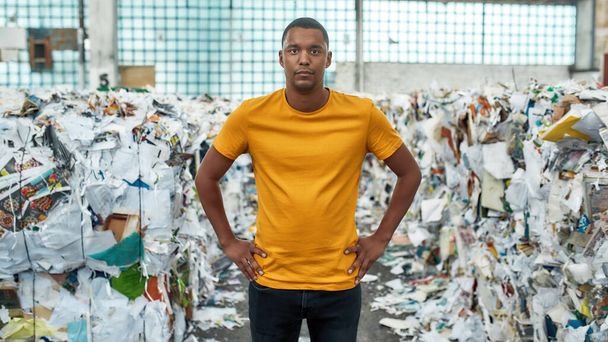 Young man standing between piles of waste paper - Fotografie, Obrázek