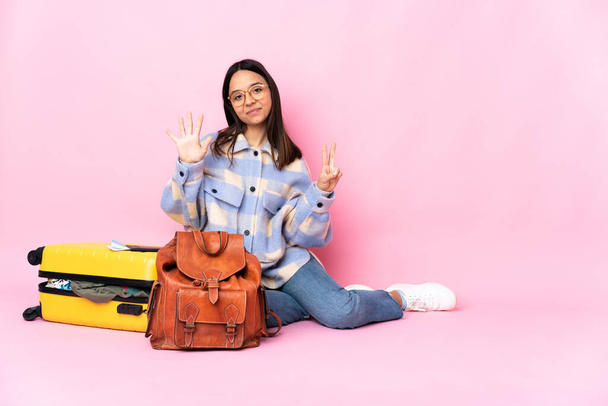 Utazó nő egy bőrönddel ül a padlón számolva hét ujjal - Fotó, kép