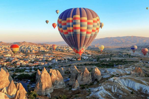 GOREME, TURKEY - PAŹDZIERNIK 4, 2020: Wiele balonów unosi się w powietrzu nad Kapadocją w pierwszych promieniach wschodzącego słońca. - Zdjęcie, obraz