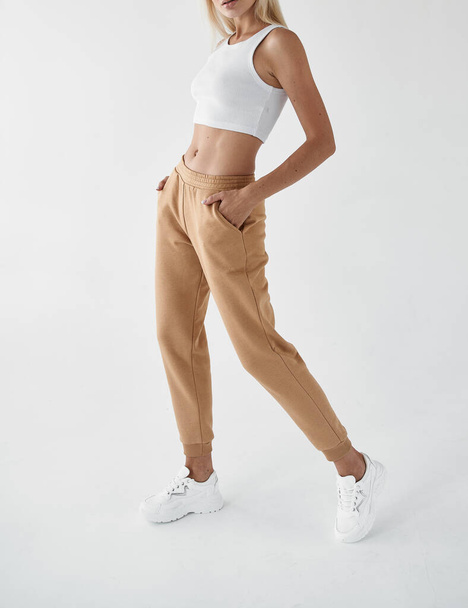 mujer usa pantalones caqui. chica en forma está de pie en joggers beige - Foto, Imagen