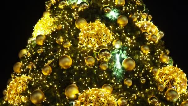 Cierra las luces de un árbol de Navidad brillando por la noche. El abeto de Año Nuevo con adornamientos y la iluminación. Fondo decoraciones árbol de Navidad. Muchas grandes bolas de oro en abeto Año Nuevo y Navidad - Imágenes, Vídeo