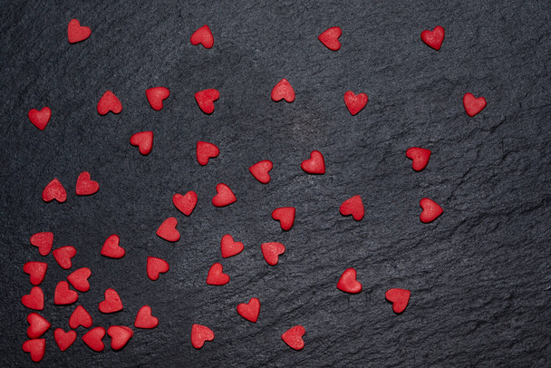 Los corazones rojos se dispersan sobre un fondo negro. El concepto del Día de San Valentín - Foto, imagen