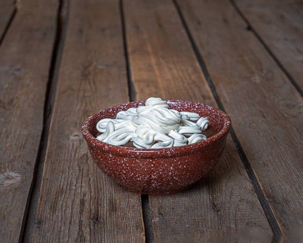 Bread soup with whipped cream in a deep bowl on an unpainted table - Photo, image