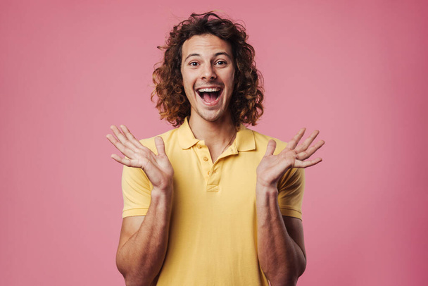 Excited handsome guy pointing expressing surprise on camera isolated over pink background - Valokuva, kuva