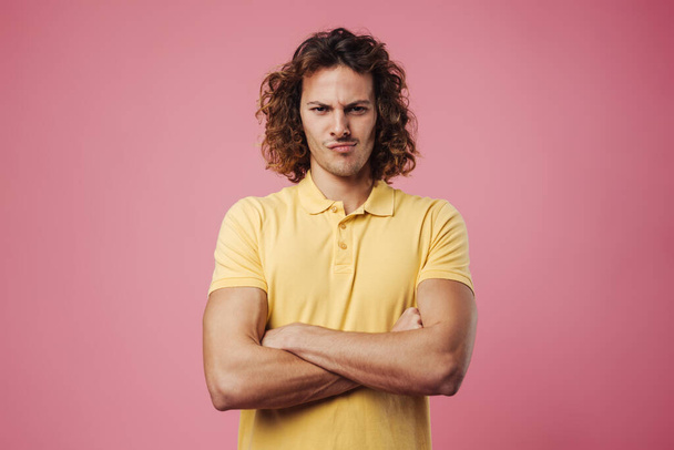 Displeased handsome guy posing with arms crossed isolated over pink background - Photo, Image