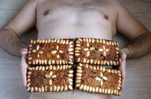 Concetto di obesità festiva. Un uomo con muffin sullo stomaco invece di una stampa.  - Foto, immagini
