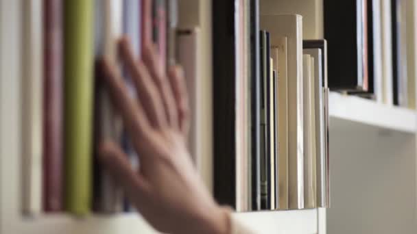 ręka kobiety poszukującej książki na półce - Materiał filmowy, wideo