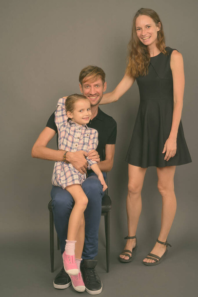 Giovane felice famiglia legame insieme contro sfondo grigio - Foto, immagini