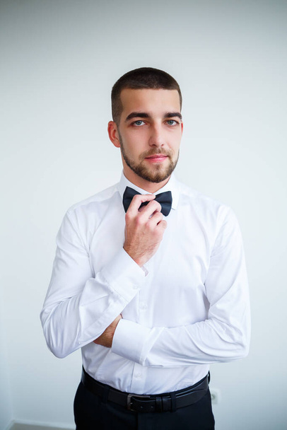 Young male businessman dressed in a white shirt with a short beard wears a black bow tie - Valokuva, kuva