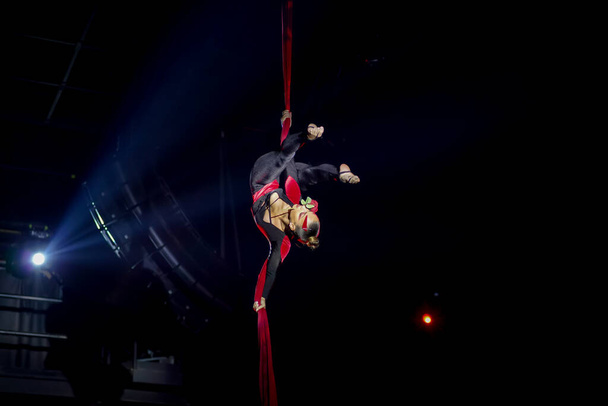 Flexible sexy athletic woman, aerial acrobatic silks performance, women upside down on aerial silks air circus show. Aerial tango, night club performance - Photo, Image