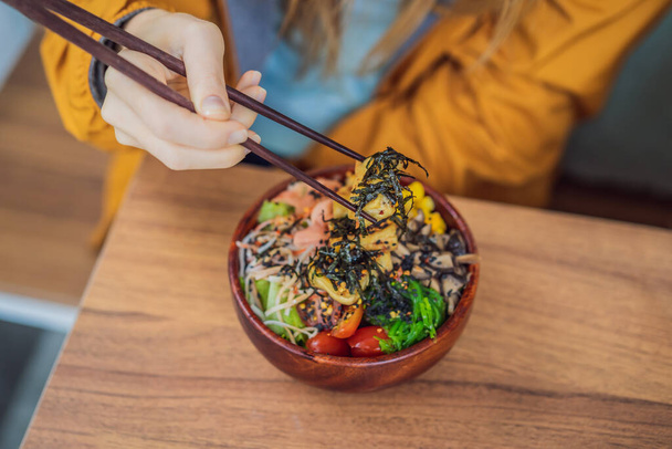 Žena jíst syrové organické Poke Bowl s rýží a zeleninou detailní záběr na stole. Pohled shora vodorovně - Fotografie, Obrázek