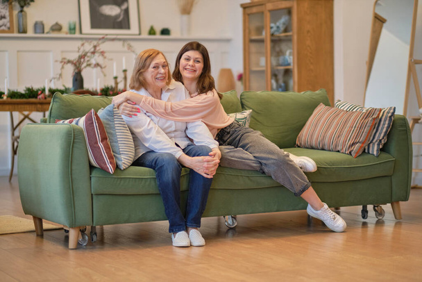 granddaughter and senior grandmother having fun enjoying talk sit on sofa, bonding chatting relaxing at home together. - Photo, Image