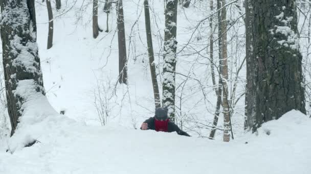 Άντρας με κόκκινη μπαντάνα με δύο μαχαίρια σκαρφαλώνει σε χιονισμένο λόφο. - Πλάνα, βίντεο