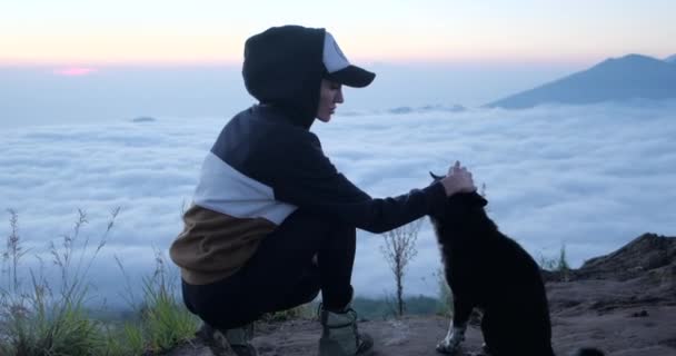 Lány ölelés szorosan a kutya és nézi táj.felhők a háttérben - Felvétel, videó