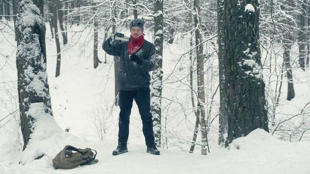 Toerist op besneeuwde heuvel schenkt zichzelf warm drankje - Foto, afbeelding