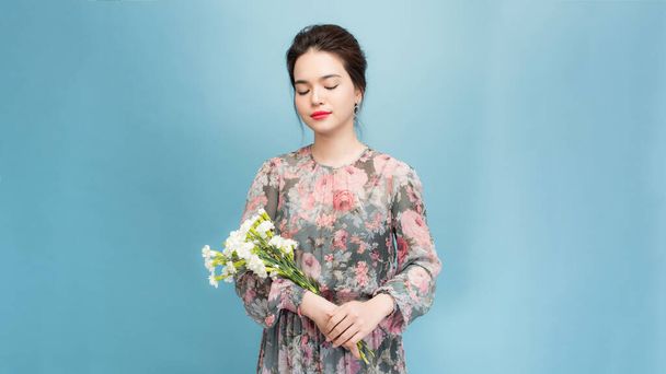 Beautiful young woman with bouquet of carnation on color background - Valokuva, kuva