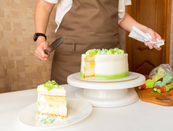 Woman in apron is cut off fresh baked Birthday cake. Homemade cake for Birthday celebration. Home baking concept. Isolated. Copy space. Leisure and hobby. - Zdjęcie, obraz