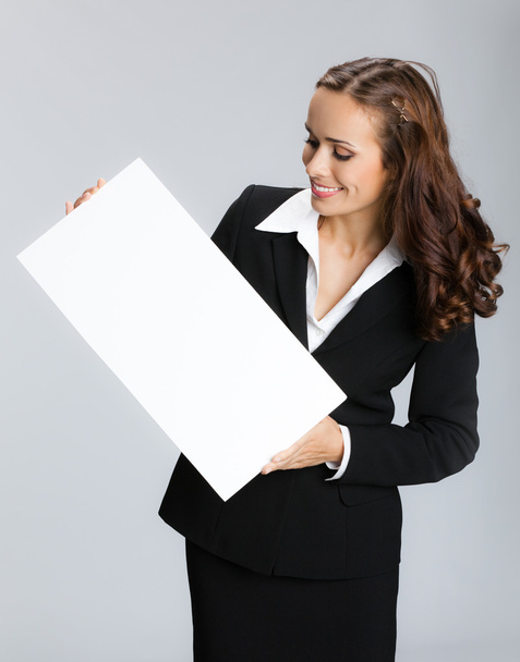 Businesswoman showing signboard, over grey - Foto, afbeelding