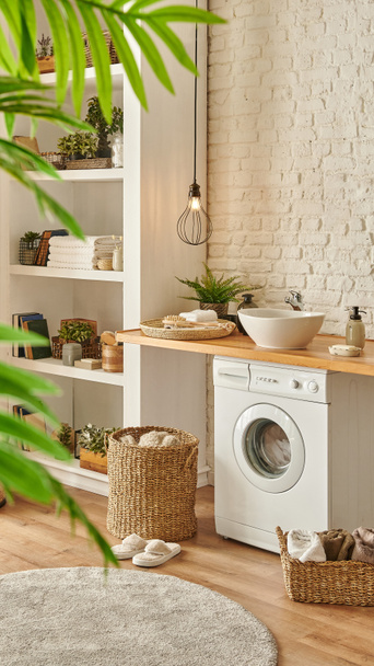 Modernes Badezimmer mit Waschmaschine und Bücherregal, Wohnaccessoires Holztisch und Waschbecken. - Foto, Bild