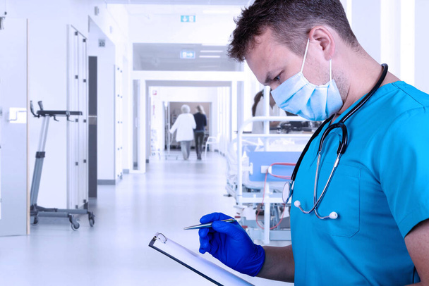 Young doctor in medical clothes examines the medical history and takes notes with a pen. Medical concept - Foto, Bild
