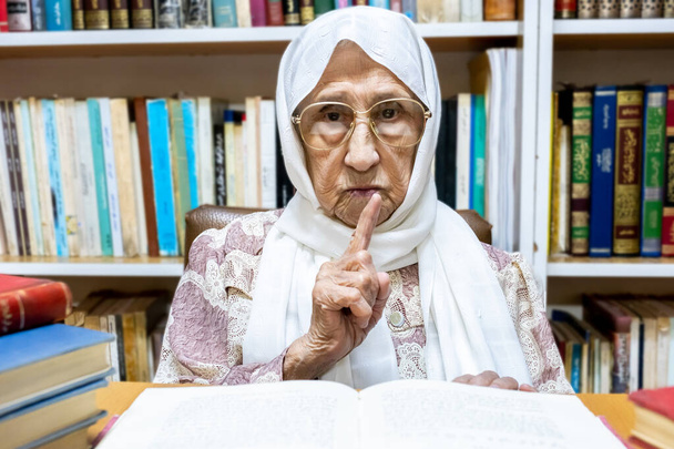 Arabisch-muslimische Frau beaufsichtigt Bibliothek und bittet die Menschen zum Schweigen - Foto, Bild