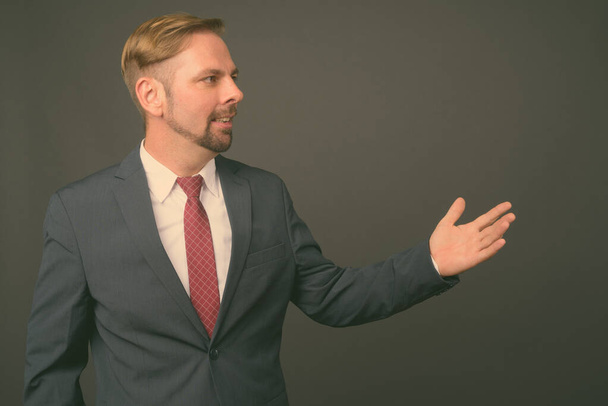 Blond bearded businessman with goatee against gray background - Photo, Image
