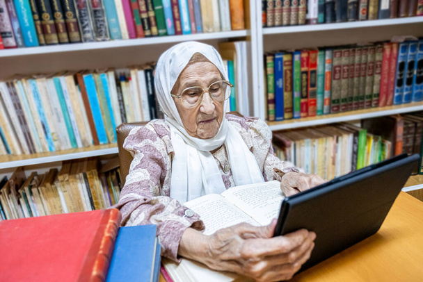 Arabská muslimka používající notebook pro čtení E-knih nad surfováním na internetu - Fotografie, Obrázek